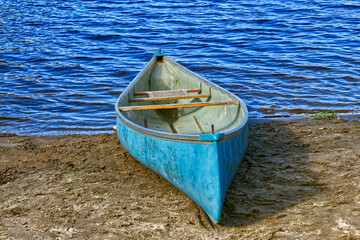 A small paddle boat parked in the shore of the lake