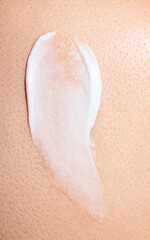 Fototapeta premium swatch of white cream on skin background, macro texture of the skin on which the cream is applied