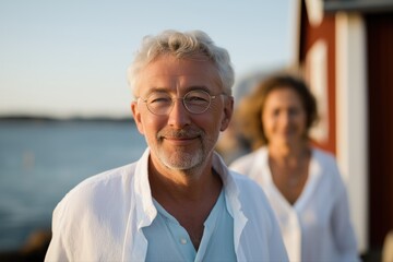 Mature caucasian couple smiling by seaside house at sunset