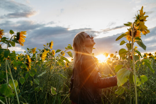 A woman walking through a field of sunflowers