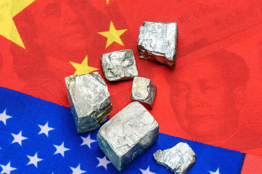 Metallic ore fragments - likely rare earth or strategic materials - laid atop overlapping Chinese and American flags. Shifting the balance in escalating China - U.S. trade and policy negotiations.