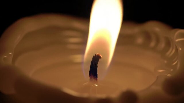 Burning Candle: A close-up shot of a lit candle flame dances elegantly against a dark backdrop, casting a warm glow. It embodies the tranquil, cozy, and romantic essence.