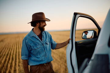 Happy farmer getting into his pick-up truck in field. © Drazen