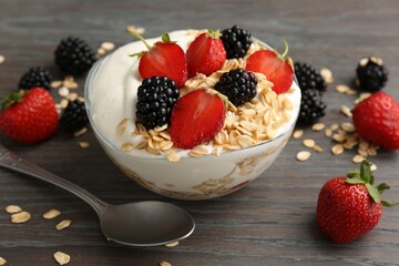 Tasty yogurt with granola and berries in bowl on wooden table, closeup