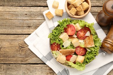 Delicious salad with croutons served on wooden table, flat lay. Space for text