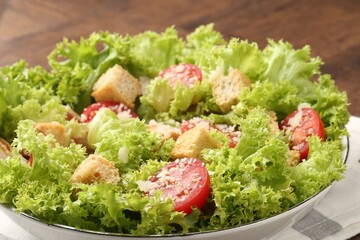 Tasty salad with croutons, tomatoes, cheese and chicken on wooden table, closeup