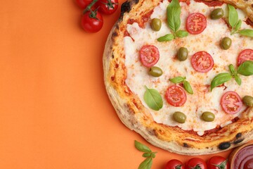 Delicious pizza with tomatoes, basil and olives served on orange background, flat lay. Space for text