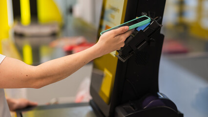 A woman pays using her smartphone at a self-checkout. 