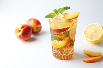 Fototapeta premium Tasty iced tea with lemon, peaches and mint on white background