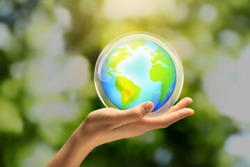 Woman holding Earth globe in hand against blurred green background, closeup. Saving environment, care about planet