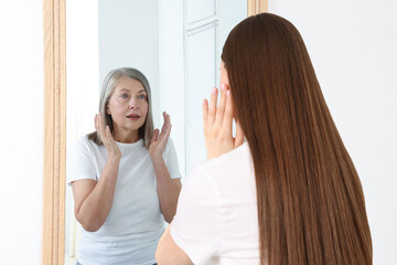 Young girl seeing herself as senior woman in mirror. Conceptual collage about past and future, flow of time, age