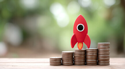 Rocket on top of stacks of coins and representing business growth and financial success