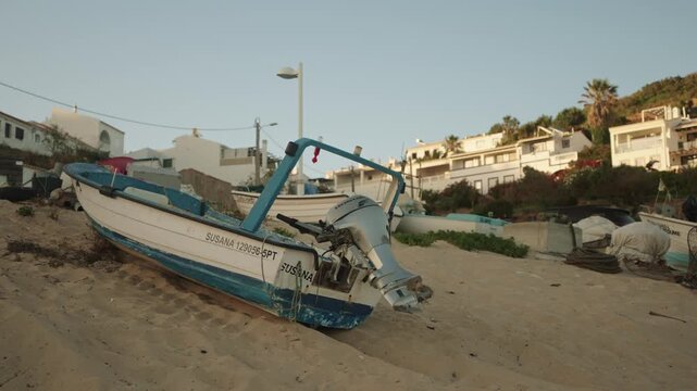 Small fishing boat with outboard motor on sandy beach in Algarve, Portugal