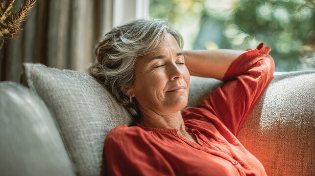 Serene senior woman relaxing peacefully on sofa, enjoying moment of calm and contentment in her home