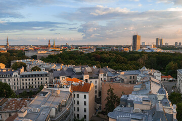 Obraz premium Riga, Latvia's old town skyline at sunset, featuring St. Peter's Church, Riga Cathedral, Jugendstil rooftops, the Riga TV Tower, and green parks.