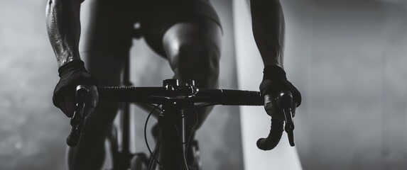 Close-up of a cyclist gripping handlebars during an indoor cycling session in a dimly lit environment