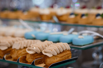 Elegant Pastry Display Featuring Cream Puffs and Macarons on Tiered Trays with Soft Lighting, Selective Focus, Golden Brown and Blue Hues.