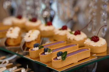 Exquisite Tartlets Display. Delicate Pastry Selection for Events. Cream, Cherry, Blueberry, Glassware, Luxury, Wedding, Dessert Table, Bokeh, Soft Focus.