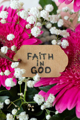 Faith in God, handwritten text on rustic paper with flowers. Close-up. Trust and belief in Jesus Christ, biblical concept.