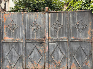 Old rusty metal gate with decorative wrought iron ornaments, vintage texture background for urban...