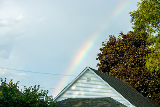 A rainbow over the house with trees