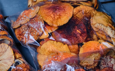 Detailed view of dried amanita mushrooms in transparent bags at an outdoor market stall. Close-Up of Packaged Dried Amanita Mushrooms