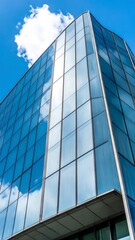 Obraz premium Modern glass skyscraper against a partly cloudy sky