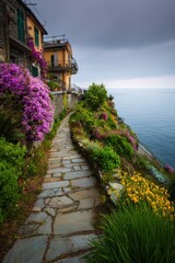 A picturesque coastal pathway, adorned with colorful blooming flowers, winds through a charming seaside village beneath a cloudy sky