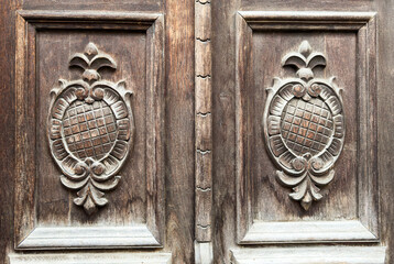 Horizontal close-up of vintage carved wooden door panels with symmetrical ornament, textured surface for design, restoration, or historical decoration projects