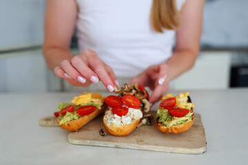 Healthy eating concept, woman makes avocado toast in bright modern kitchen.