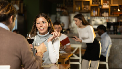 Girl in cafe sits opposite male companion, has nice conversation and discusses news of day. Cozy atmosphere of cafe, meeting place for friends, business partners, colleagues.
