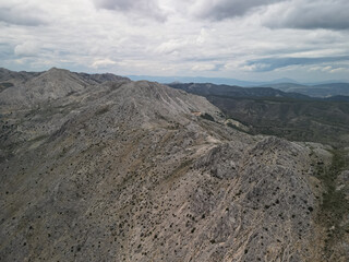 Aerial view displays barren rocky peaks and valleys of Taurus Mountains under cloudy skies showcasing dramatic karst formations typical of Turkish highland terrain with sparse vegetation