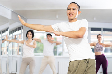 Fototapeta premium Guy conducts lesson for group of young people, demonstrates basic movements for performing locking dance, teaches modern dance culture directions