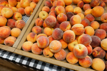 Fresh peaches displayed in wooden crates at a local farmer's market during the summer harvest season