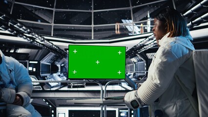 Team of cosmonauts calibrating starship sensors using isolated screen monitor, preparing for mission. Astronauts using chroma key display, beginning landing procedures on solar system planet