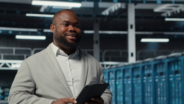 System administrator walking in server farm deploying infrastructure for efficient data analysis. Worker using device in dat a center in managing storage systems for datasets, camera B