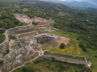Aerial view of tlos city walls agora and hillside dwellings over green fields Fethiye district mugla Turkiye Masonry and tombs visible Broad panorama across the valley Travel and education content