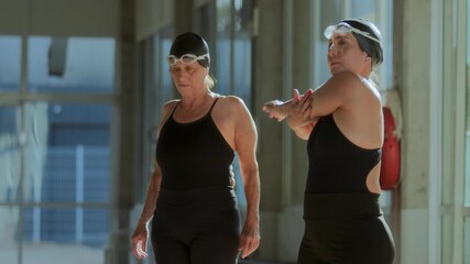 Female swimmers stretching by poolside before training
