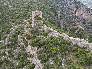 Aerial view of ridge top fortress ruins at Tlos near Fethiye in Mugla Turkiye long walls trace a rocky spine over deep valleys sunset haze and Taurus peaks create epic mood heritage and history feel
