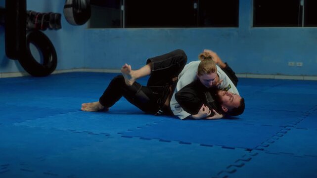 Man and woman training Brazilian Jiu-Jitsu grappling on mat