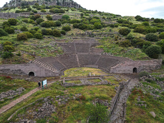 Ancient amphitheater in Assos Turkey with stone seating and arches The site is surrounded by green hills and scattered ruins It shows historical architecture and scenic nature