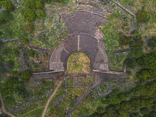 Ancient amphitheater in Assos Turkey with stone steps and curved seating Hills and ruins surround the structure showing a blend of history and nature on a cloudy day