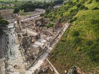 Aerial view along curetes street toward the library district, ruins line both sides with columns and walls, the hillside adds greenery and depth, this is ephesus in Turkey known for classical heritage