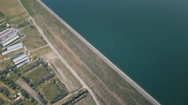 Aerial: Djizak Reservoir dam with canal system, agricultural fields, ponds, and rural roads. Water flows through channels, supporting farmland and showing intricate irrigation infrastructure