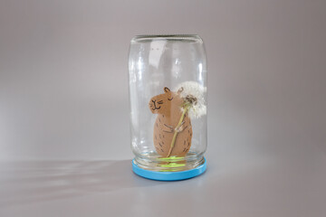 Creative paper sculpture of capybara holding flower in upside-down jar with blue base, ideal for handmade product visuals, storytelling guides, kids craft tutorials, eco-friendly educational content,