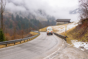 Propane tank truck on a curvy mountain road on a rainy  and foggy winter day