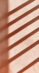 Diagonal shadows cast by parallel slats on a pale peach textured wall, creating a striped pattern of light and shadow