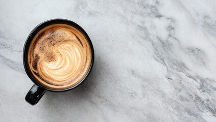 Overhead view of a dark mug of latte art coffee on a gray marble surface.  The coffee features a swirling design and a thin layer of crema