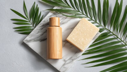 Bamboo bottle and bar soap rest on marble, adorned by palm fronds on a gray background