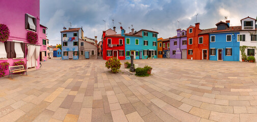 Colorful houses surrounding a paved square in Burano Venice Italy.